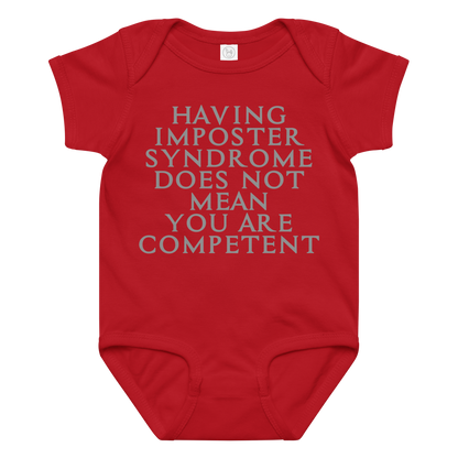 "Having Imposter Syndrome does not mean you are competent" printed on a red baby jersey bodysuit laying on a flat surface amongst other clothes