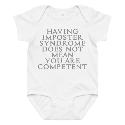 "Having Imposter Syndrome does not mean you are competent" printed on a white baby jersey bodysuit laying on a flat surface amongst other clothes