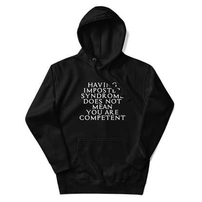 "Having Imposter Syndrome does not mean you are competent" printed on a black unisex hoodie laying on a flat surface with the hood up