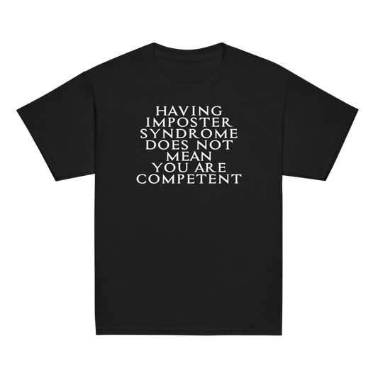 "Having Imposter Syndrome does not mean you are competent" printed on a black youth classic tee laying on a flat surface