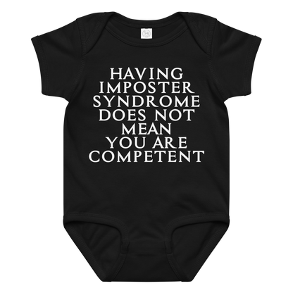 "Having Imposter Syndrome does not mean you are competent" printed on a black baby jersey bodysuit laying on a flat surface amongst other clothes