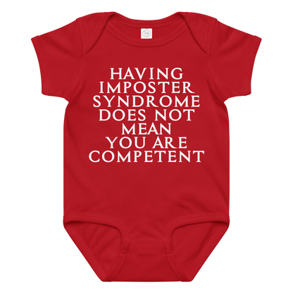 "Having Imposter Syndrome does not mean you are competent" printed on a red baby jersey bodysuit laying on a flat surface amongst other clothes