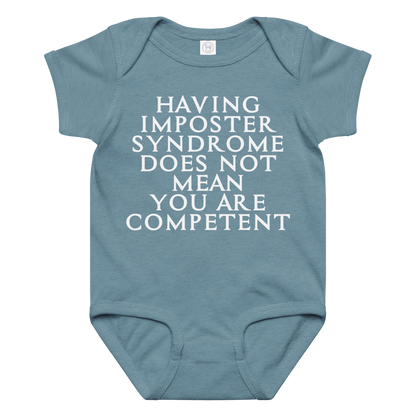 "Having Imposter Syndrome does not mean you are competent" printed on a vintage indigo baby jersey bodysuit laying on a flat surface amongst other clothes
