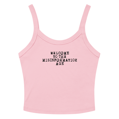 "Welcome to the misinformation age" printed on a solid pink blend women's micro-rib tanktop laying on a flat surface amongst sunglasses and shorts