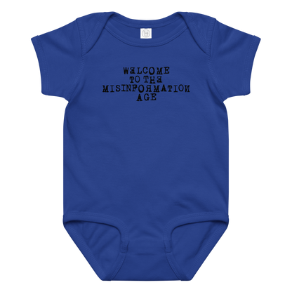 "Welcome to the misinformation age" printed on a royal baby jersey bodysuit laying on a flat surface amongst other clothes