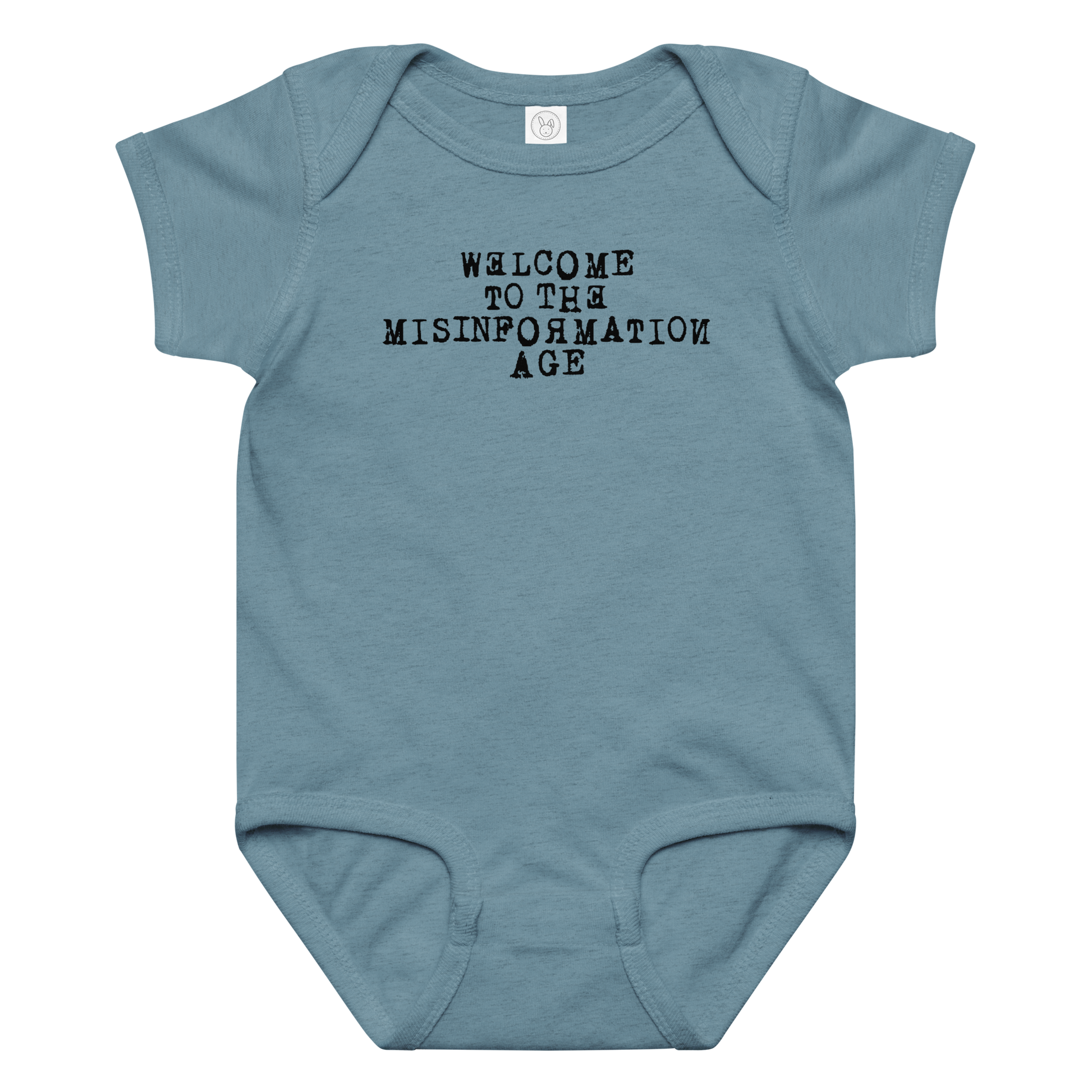"Welcome to the misinformation age" printed on a vintage indigo baby jersey bodysuit laying on a flat surface amongst other clothes