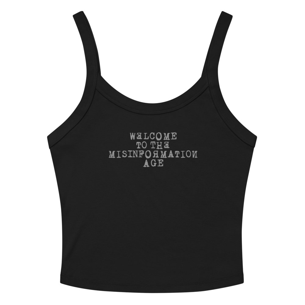 "Welcome to the misinformation age" printed on a solid black blend women's micro-rib tanktop laying on a flat surface amongst sunglasses and shorts