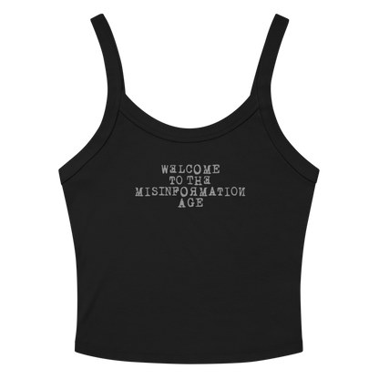 "Welcome to the misinformation age" printed on a solid black blend women's micro-rib tanktop laying on a flat surface amongst sunglasses and shorts