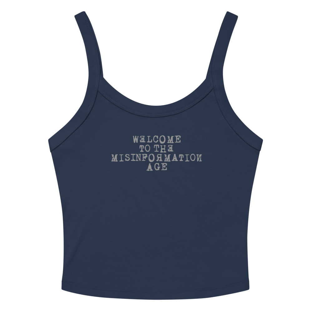 "Welcome to the misinformation age" printed on a solid navy blend women's micro-rib tanktop laying on a flat surface amongst sunglasses and shorts