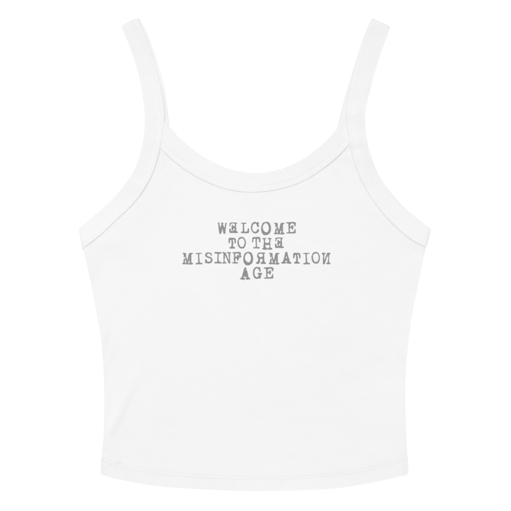 "Welcome to the misinformation age" printed on a solid white blend women's micro-rib tanktop laying on a flat surface amongst sunglasses and shorts