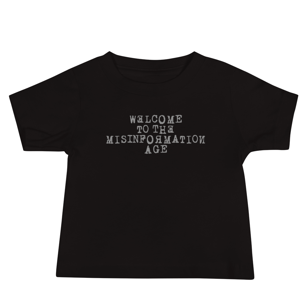 "Welcome to the misinformation age" printed on a black baby jersey short sleeve tee laying on a flat surface