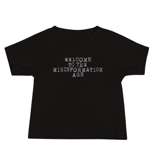 "Welcome to the misinformation age" printed on a black baby jersey short sleeve tee laying on a flat surface