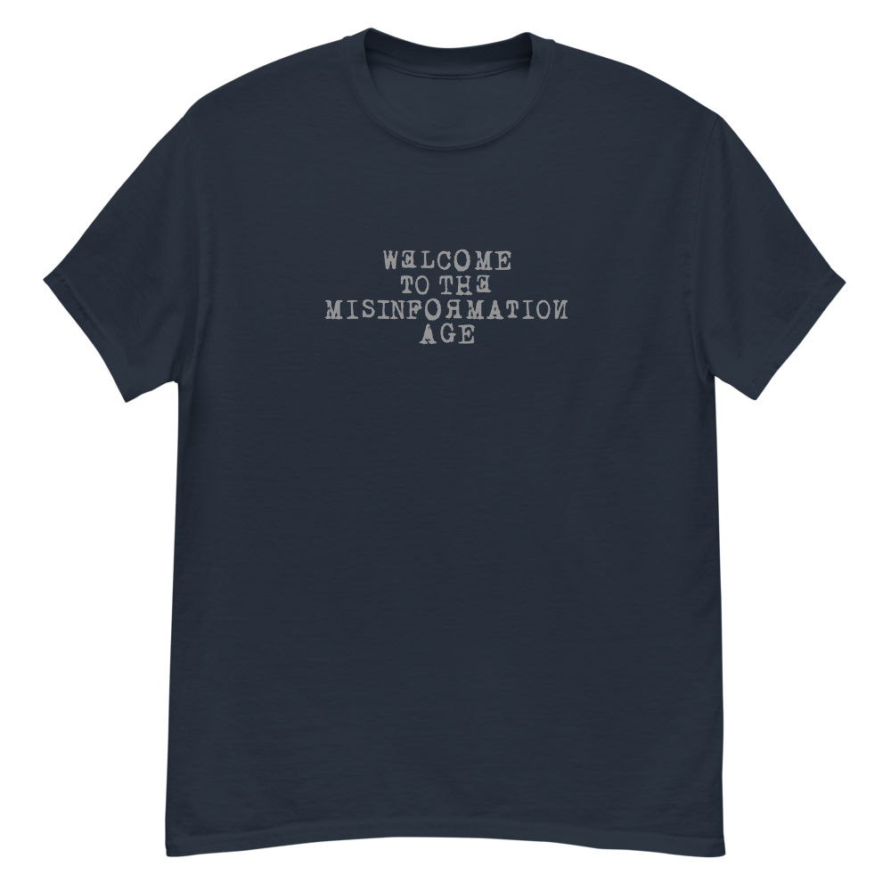 "Welcome to the misinformation age" printed on a navy unisex classic tee laying on a flat surface