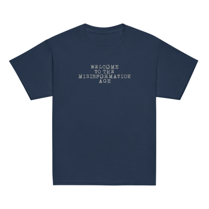 "Welcome to the misinformation age" printed on a navy youth classic tee laying on a flat surface