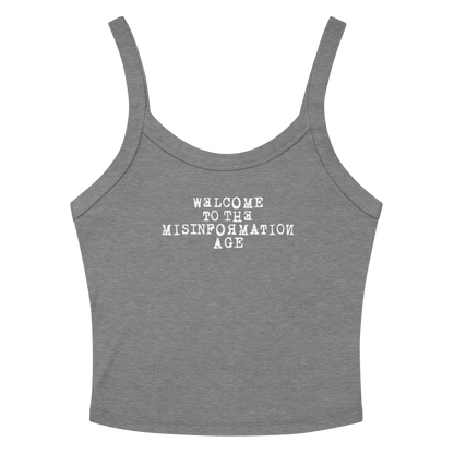 "Welcome to the misinformation age" printed on a athletic heather women's micro-rib tanktop laying on a flat surface amongst sunglasses and shorts