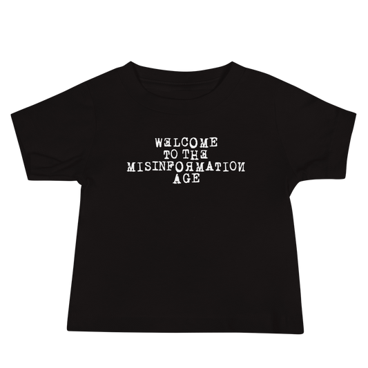 "Welcome to the misinformation age" printed on a black baby jersey short sleeve tee laying on a flat surface