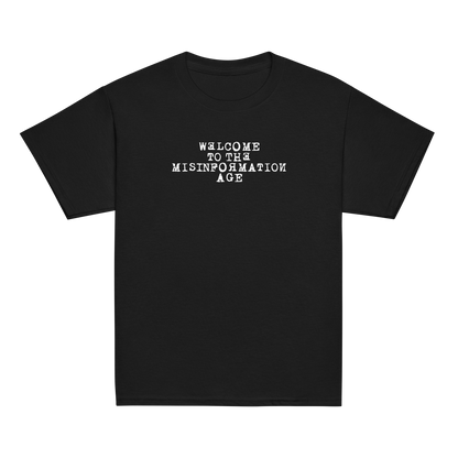"Welcome to the misinformation age" printed on a black youth classic tee laying on a flat surface