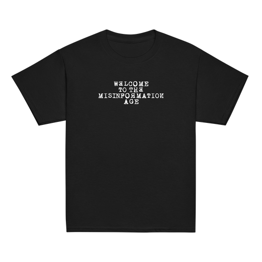 "Welcome to the misinformation age" printed on a black youth classic tee laying on a flat surface