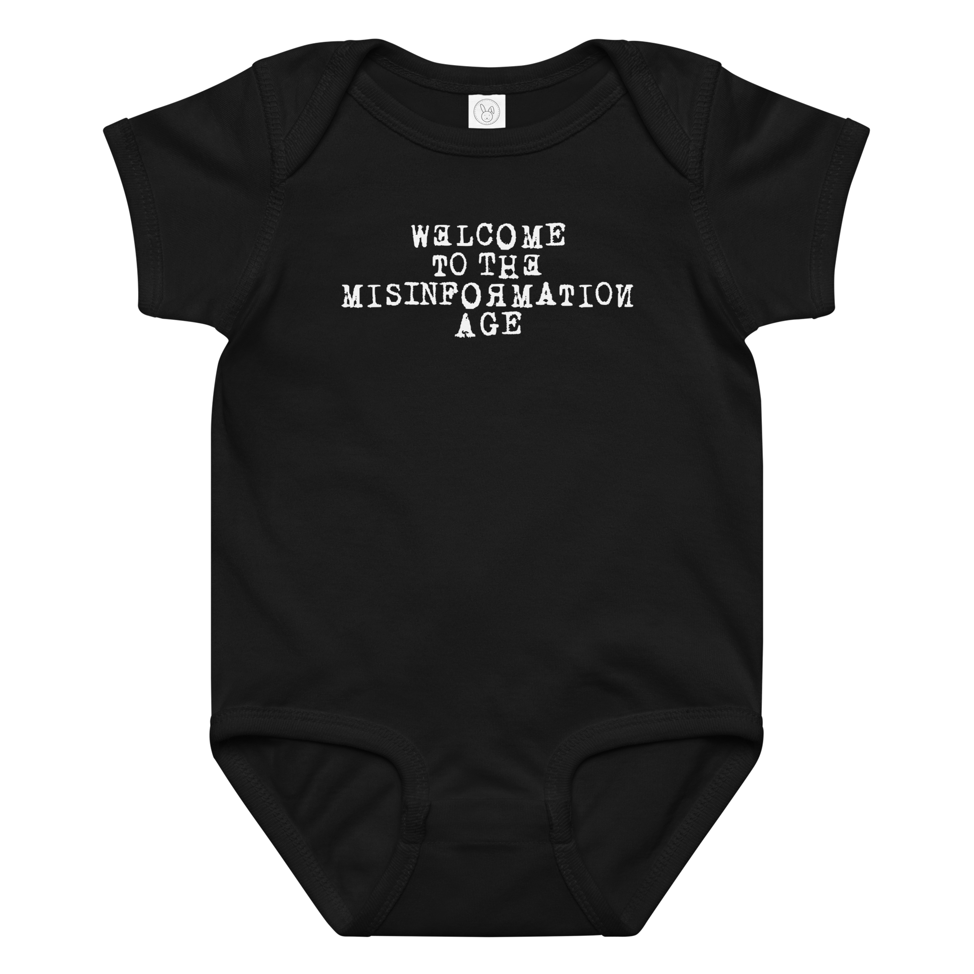 "Welcome to the misinformation age" printed on a black baby jersey bodysuit laying on a flat surface amongst other clothes