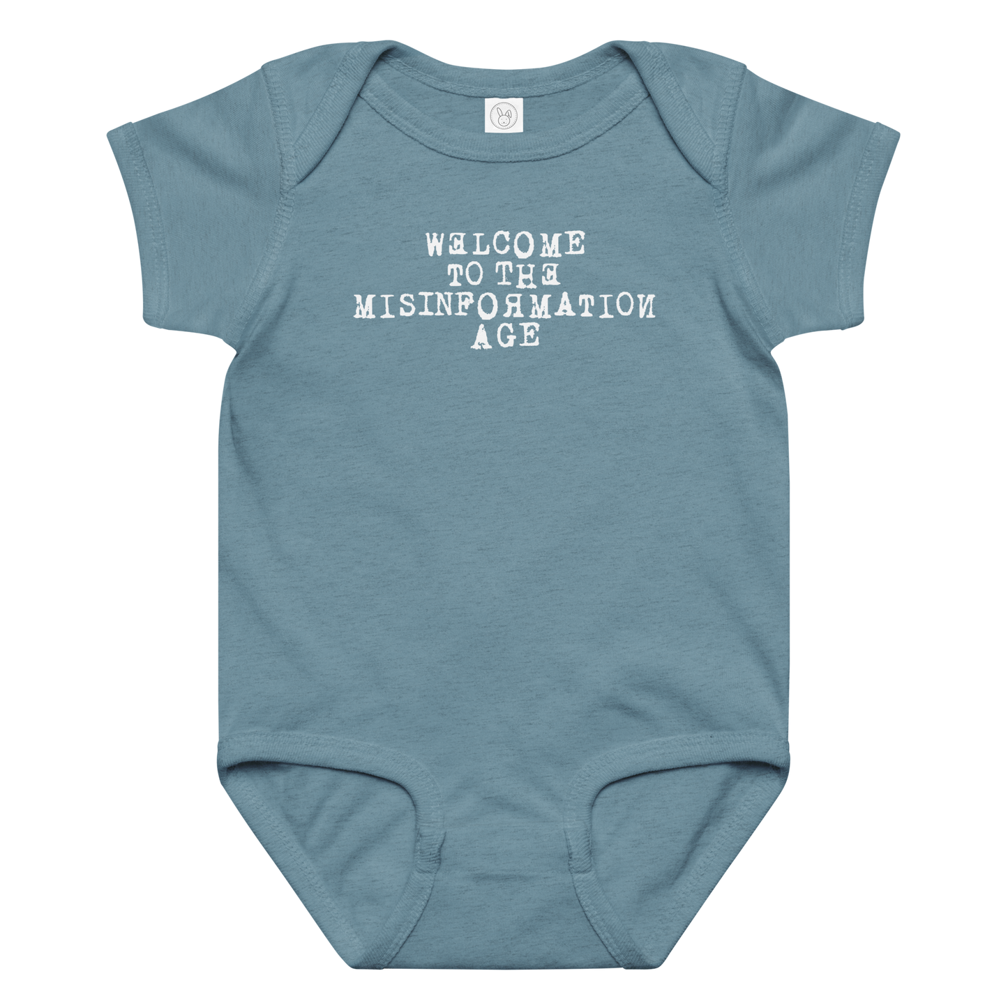 "Welcome to the misinformation age" printed on a vintage indigo baby jersey bodysuit laying on a flat surface amongst other clothes