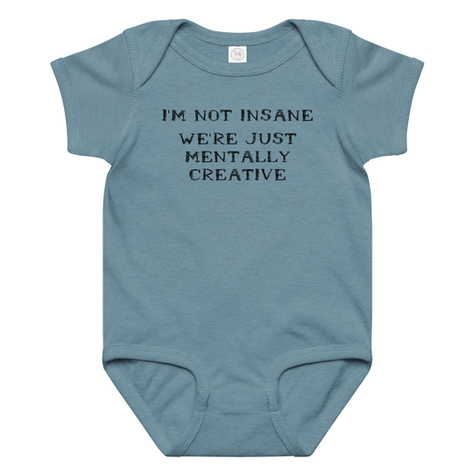 "I’m not insane   We’re just mentally creative" printed on a vintage indigo baby jersey bodysuit laying on a flat surface amongst other clothes