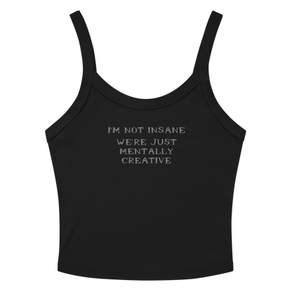 "I’m not insane   We’re just mentally creative" printed on a solid black blend women's micro-rib tanktop laying on a flat surface amongst sunglasses and shorts