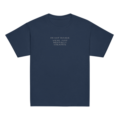 "I’m not insane   We’re just mentally creative" printed on a navy youth classic tee laying on a flat surface