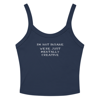 "I’m not insane   We’re just mentally creative" printed on a solid navy blend women's micro-rib tanktop laying on a flat surface amongst sunglasses and shorts