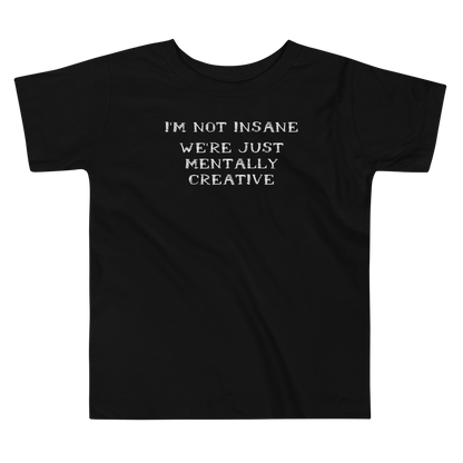 "I’m not insane   We’re just mentally creative" printed on a black toddler short sleeve tee laying on a flat surface