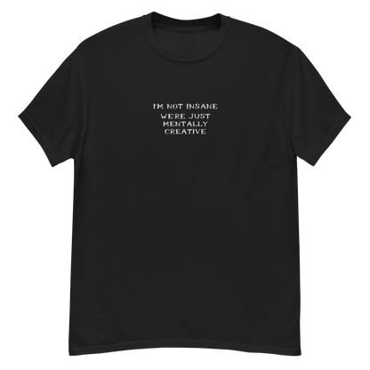 "I’m not insane   We’re just mentally creative" printed on a black unisex classic tee laying on a flat surface