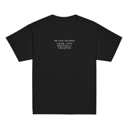 "I’m not insane   We’re just mentally creative" printed on a black youth classic tee laying on a flat surface