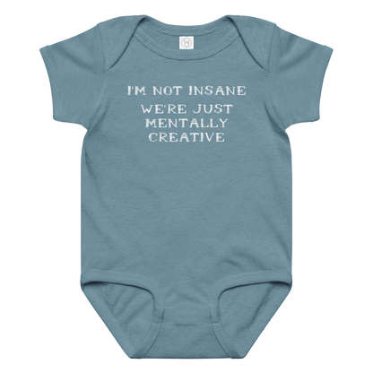 "I’m not insane   We’re just mentally creative" printed on a vintage indigo baby jersey bodysuit laying on a flat surface amongst other clothes
