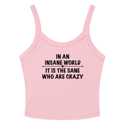 "In an insane world, it is the sane who are crazy" printed on a solid pink blend women's micro-rib tanktop laying on a flat surface amongst sunglasses and shorts