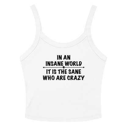 "In an insane world, it is the sane who are crazy" printed on a solid white blend women's micro-rib tanktop laying on a flat surface amongst sunglasses and shorts