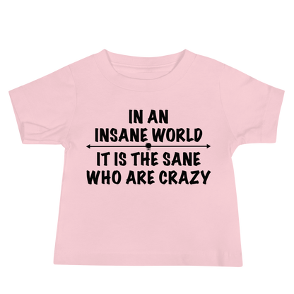 "In an insane world, it is the sane who are crazy" printed on a pink baby jersey short sleeve tee laying on a flat surface