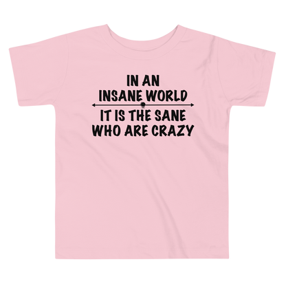"In an insane world, it is the sane who are crazy" printed on a pink toddler short sleeve tee laying on a flat surface