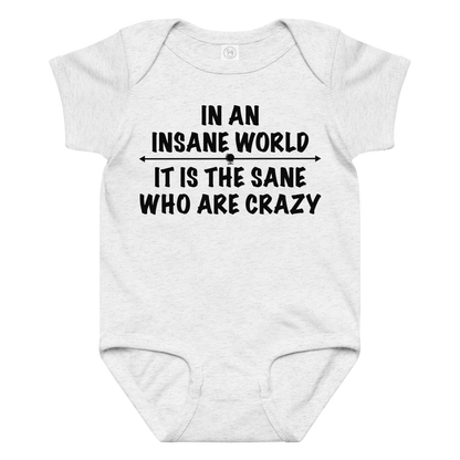 "In an insane world, it is the sane who are crazy" printed on a ash baby jersey bodysuit laying on a flat surface amongst other clothes