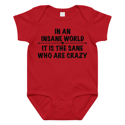 "In an insane world, it is the sane who are crazy" printed on a red baby jersey bodysuit laying on a flat surface amongst other clothes