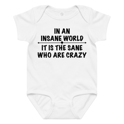 "In an insane world, it is the sane who are crazy" printed on a white baby jersey bodysuit laying on a flat surface amongst other clothes