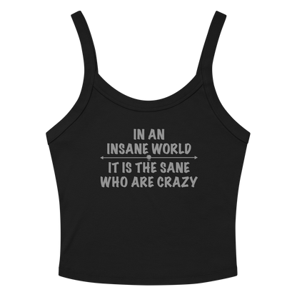 "In an insane world, it is the sane who are crazy" printed on a solid black blend women's micro-rib tanktop laying on a flat surface amongst sunglasses and shorts