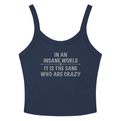 "In an insane world, it is the sane who are crazy" printed on a solid navy blend women's micro-rib tanktop laying on a flat surface amongst sunglasses and shorts
