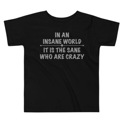 "In an insane world, it is the sane who are crazy" printed on a black toddler short sleeve tee laying on a flat surface