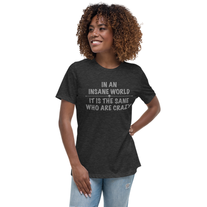 "In an insane world, it is the sane who are crazy" printed on a dark grey heather women's relaxed t-shirt worn by a female