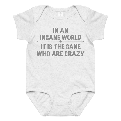 "In an insane world, it is the sane who are crazy" printed on a ash baby jersey bodysuit laying on a flat surface amongst other clothes