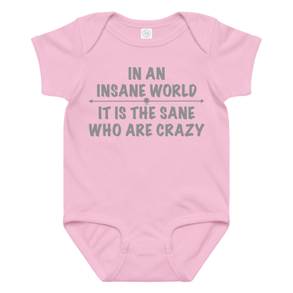 "In an insane world, it is the sane who are crazy" printed on a pink baby jersey bodysuit laying on a flat surface amongst other clothes