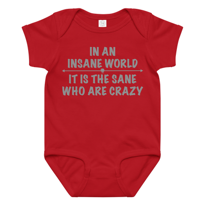 "In an insane world, it is the sane who are crazy" printed on a red baby jersey bodysuit laying on a flat surface amongst other clothes