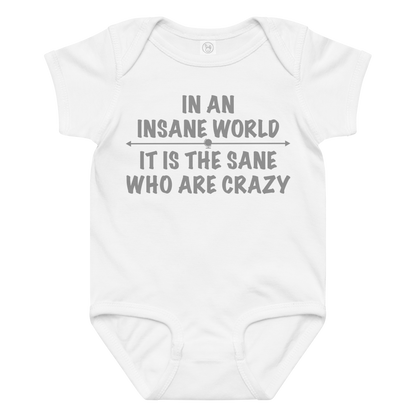 "In an insane world, it is the sane who are crazy" printed on a white baby jersey bodysuit laying on a flat surface amongst other clothes