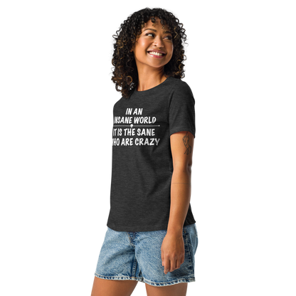 "In an insane world, it is the sane who are crazy" printed on a dark grey heather women's relaxed t-shirt worn by a female