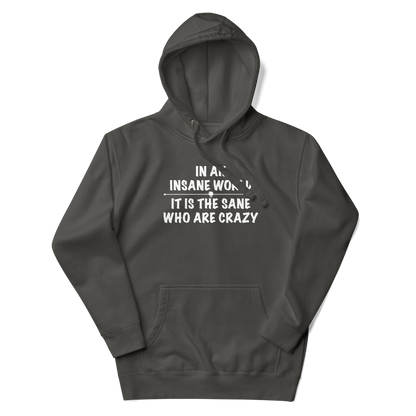 "In an insane world, it is the sane who are crazy" printed on a vintage black unisex hoodie laying on a flat surface with the hood up