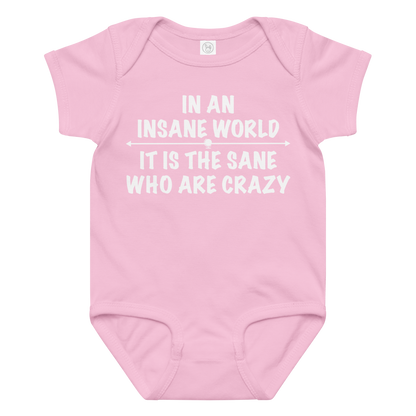 "In an insane world, it is the sane who are crazy" printed on a pink baby jersey bodysuit laying on a flat surface amongst other clothes